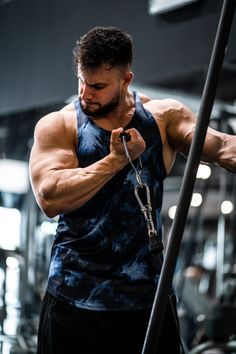 a man is working out with a pull up bar in the gym while looking down at his arm