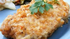 a piece of chicken with parsley on top of it sitting on a blue plate