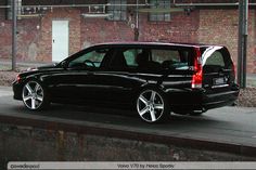 a black car parked next to a brick building