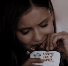 a young woman biting into a package of candy with the words mystic falls hospital on it