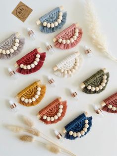 six different colored hair clips with white beads and feathers on the top one is made from fabric