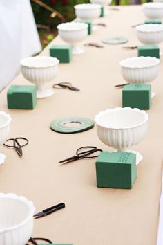 the table is covered with green and white bowls, scissors, and other things on it