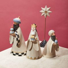 three figurines sitting on top of a table next to a star and a pink wall