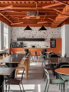 an empty restaurant with tables and chairs in front of the counter, along with orange painted walls