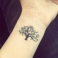 a small tattoo on the wrist of a woman's arm, depicting a tree