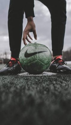 a person standing next to a green soccer ball