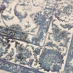 a blue and white area rug with an ornate design on the center, surrounded by smaller floral designs