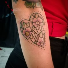 a woman with a tattoo on her arm has a heart and flowers in the middle