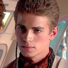 a young man with braids on his hair looks at the camera while standing next to another person