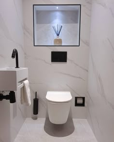 a white toilet sitting next to a sink in a bathroom under a window with lights