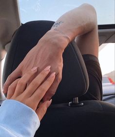 two people holding hands in the back seat of a car, with one person's hand on the other