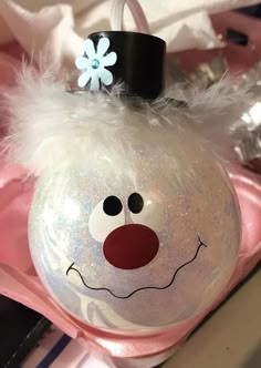 a christmas ornament with a snowman face on it's head and a flower in its hair