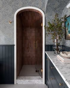 a bathroom with marble counter tops and black cabinets, along with an arched shower door