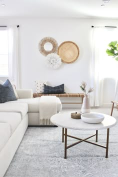 a living room filled with white furniture and lots of pillows on top of it's walls