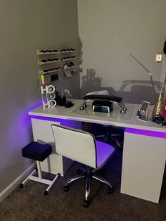 a white desk with two chairs and a phone on top of it in front of a gray wall