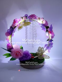 an arrangement of flowers and butterflies is displayed in a circular light - up display case