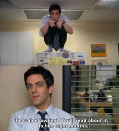 a man is sitting on top of a cubicle and pointing at the camera with his finger