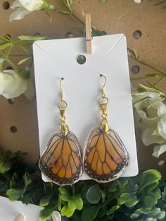 a pair of earrings with a butterfly wing hanging from it