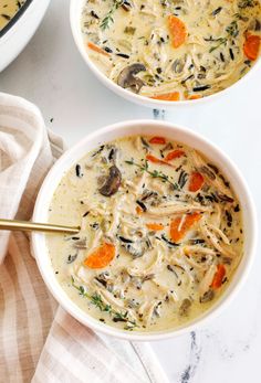 two bowls filled with soup on top of a white counter next to a bowl of chicken noodle soup