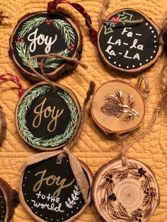 christmas ornaments are hanging on a table with some words painted on them and pine cones