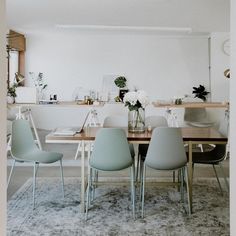 a dining room table with four chairs and a vase filled with flowers on top of it