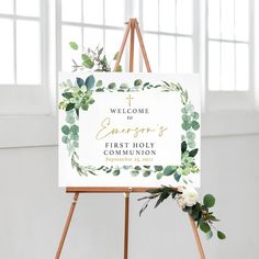 a welcome sign on an easel with greenery