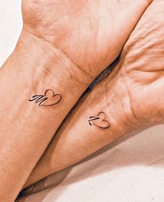 two people with matching tattoos on their wrists, one is holding the other's hand