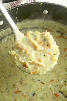 a ladle full of soup with broccoli and carrots in it is being held by a spoon