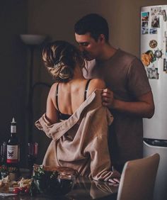 a man and woman standing in front of a refrigerator with food on the counter next to it