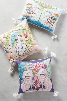 three decorative pillows with pom poms on them sitting on a white counter top