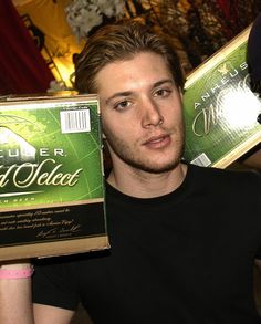 a young man holding up a box of beer