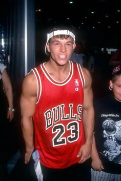 a young man in a bulls jersey standing next to a little boy wearing a headband