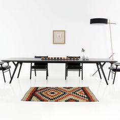 a dining table with chairs and a rug on the floor