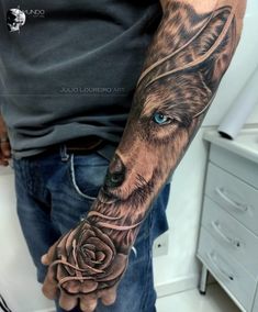 a man's arm with a wolf and rose tattoo on his left hand,