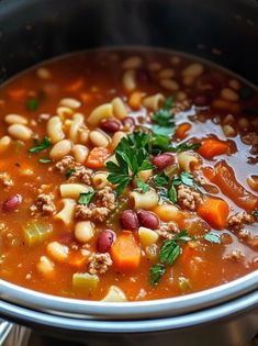 a close up of a bowl of soup with meat, beans and parsley in it