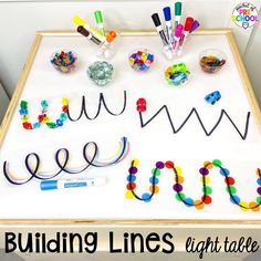 a table topped with lots of crafting supplies on top of a white board that says building lines