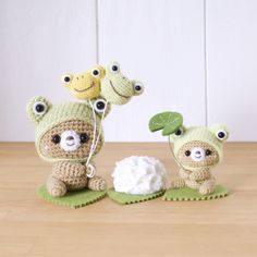 there are three stuffed animals on the table with one holding a green leaf and another standing next to it