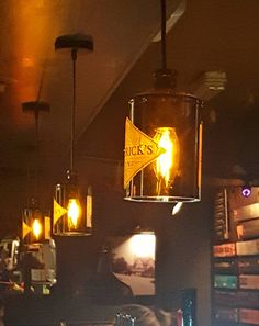 some lights hanging from the ceiling in a bar with people sitting at tables and drinking