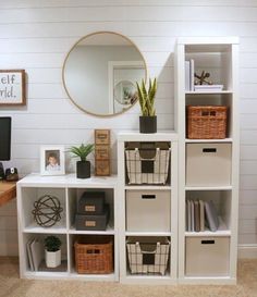 a white shelf filled with lots of boxes and baskets next to a wall mounted mirror