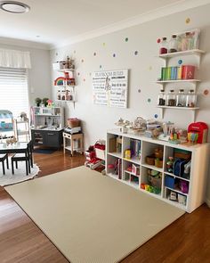 a child's playroom with lots of toys on the floor and shelves filled with books