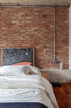 a bedroom with brick walls and white bedding