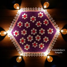 a purple and white doily with candles around it on a wooden table top in the dark