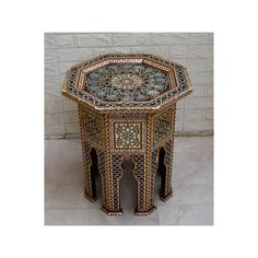 an intricately decorated table sits in front of a white brick wall and stone floor