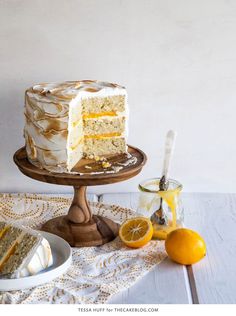 a white cake sitting on top of a wooden table next to sliced lemons and orange slices