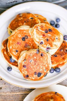 pancakes with blueberries and syrup on a white plate