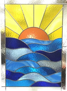 a stained glass window with the sun setting in the sky and water on it's surface