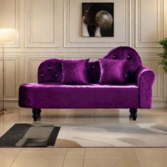 a purple couch sitting in a living room next to a lamp