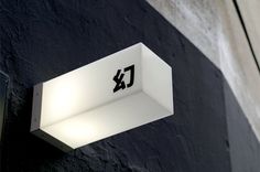 a close up of a light on the side of a building with a black and white wall