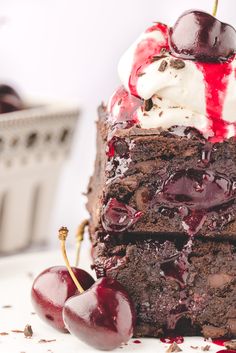 a piece of cake with ice cream and cherries on top, sitting next to two cherries