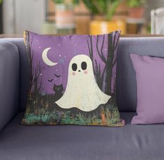 a pillow with a ghost on it sitting on a couch next to a purple pillow